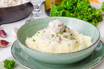 Meatballs in a creamy sauce with mushrooms and mashed potatoes in a plate