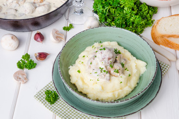 Meatballs in a creamy sauce with mushrooms and mashed potatoes in a plate