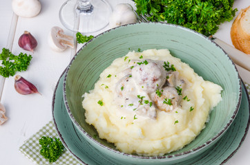 Meatballs in a creamy sauce with mushrooms and mashed potatoes in a plate