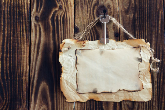 hanging key and scorched paper on a wooden background