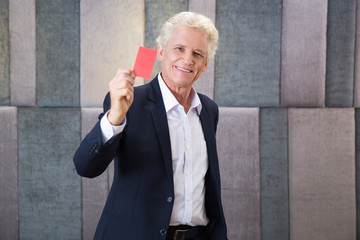 Smiling senior businessman showing red card