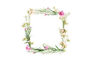 Wreath frame made of pink and beige wildflowers, green leaves, branches on white background. Flat lay, top view. Valentine's background