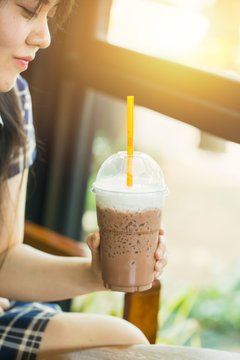 asian cute teen woman drinking ice cool milk chocolate or cocoa at summer season in hot day for healthy drink . happy modern lifestyle at the cafe