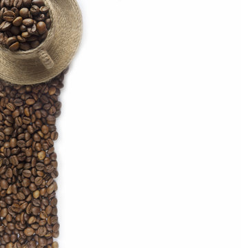 Coffee beans and a cup at border of image with copy space for text. Coffee background or texture concept.