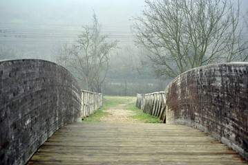 ponte su un ruscello in pietra e legno con la nebbia in inverno