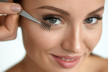 Beautiful Woman Applying Black Long Fake Eyelashes With Tweezers