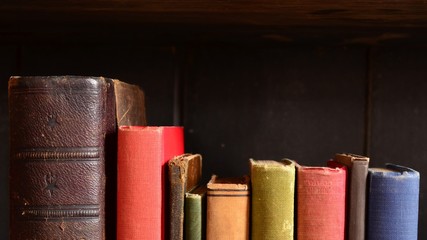 Row of colorful vintage books on an old wooden bookshelf