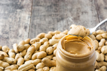 Creamy peanut butter and spoon on wooden background
