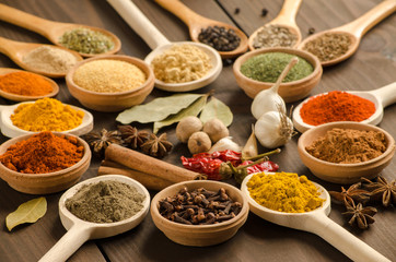 Powder spices on mixing spoons at wooden table 