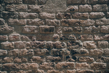 Brick wall architectural background texture with burned black areas and areas filled with cement on sunny summer day, Barcelona, Spain