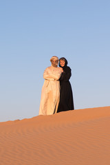 Fototapeta na wymiar Couple dressed in traditional arabic dress in desert of Dubai, UAE.