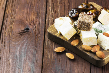 Oriental sweets, dates and nuts on a dark wooden background. Cop