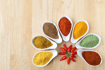 Aromatic and colorful spices in ceramic containers on a wooden background.