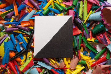 The square cut out of the paper lies on a pile of shavings from pencil sharpeners.
