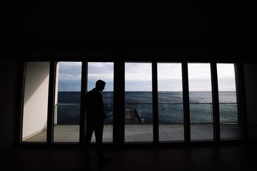 Fototapeta na wymiar silhouette of a man in the office on the horizon of the sea, panoramic Windows