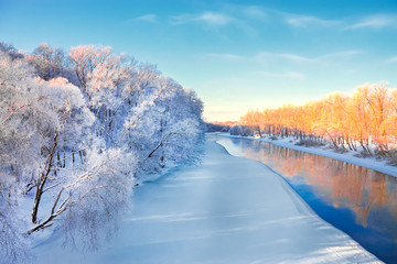 River with ice-covered trees at sunset December bright winter day in sunlight