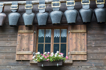 Old window with open shutters decorated with flowers and bells