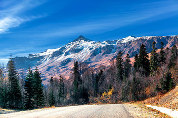 Big mountain in autumn with yellow trees and snow-capped mountain view from the road serpentine Caucasus