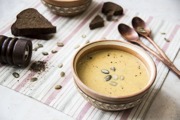 pumpkin soup with cream and pumpkin seeds in clay plates with wooden spoons for two