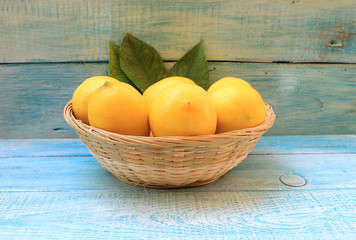 Ripe yellow lemons in a basket on a blue background