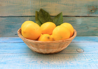 Ripe yellow lemons in a basket on a blue background