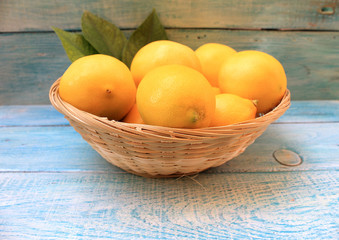 Ripe yellow lemons in a basket on a blue background