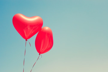 Fototapeta na wymiar Two red heart shaped balloons in flight