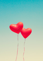 Naklejka na ściany i meble Two red heart shaped balloons in flight