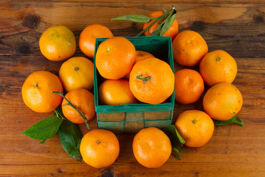 tangerine orange fruits in green box on old wooden background top view