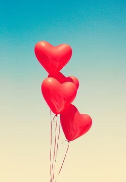 Various red heart shaped balloons in flight