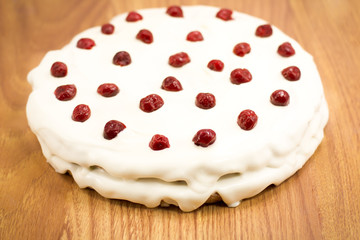 cream cake with cherries on a thin wooden table