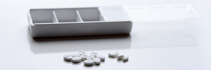 Medikamente mit Aufbewahrungsbox auf weißer Unterlage