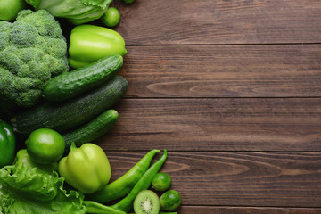 Green vegetables and fruits on wooden background