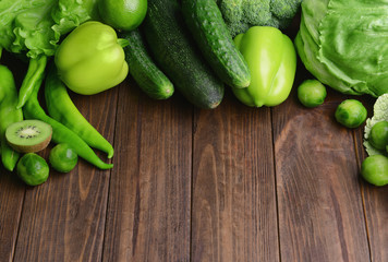 Green vegetables and fruits on wooden background