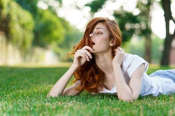 red-haired woman lying in the park on the grass
