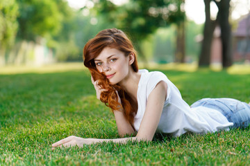 Naklejka na ściany i meble red-haired woman lying in the park on the grass