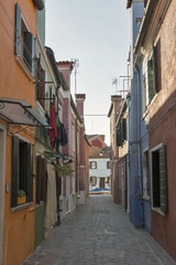 Fototapeta na wymiar Narrow Mediterranean style street on Burano island, Italy.
