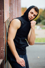 Portrait of a strong handsome man in training cloth. Posing in the hood.