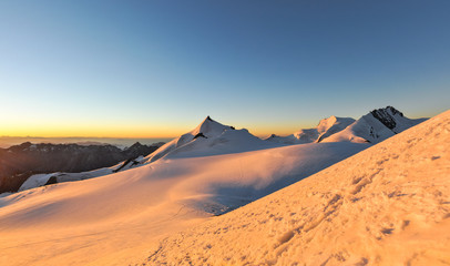 Fototapeta na wymiar XXL panorama of sunrise at 3800m amsl in the Swiss Wallis Alps near the summit of Alphubel (4206m).Allalinhorn, Strahlhorn & Rimpfischhorn in the background (left to right).Snow fields in foreground.