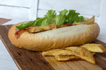 Barbecue Grilled Hot Dog with ketchup, french fries and Cherry tomatoes on wooden background