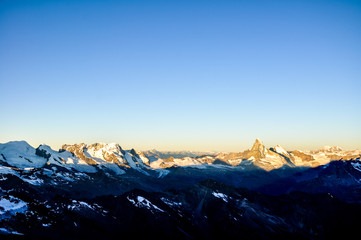 Sunrise at 3800m amsl in the Swiss Wallis Alps near the summit of Alphubel (4206m).  Castor, Pollux, Breithorn, Matterhorn & Mont Blanc in the background (left to right). Snow field in foreground.