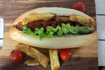 Barbecue Grilled Hot Dog with ketchup, french fries and Cherry tomatoes on wooden background