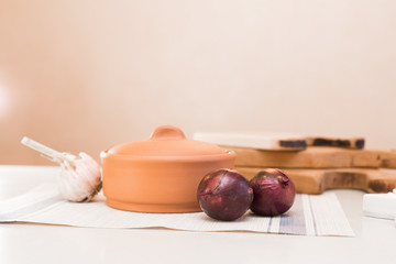clay pot, garlic and red onions on the table
