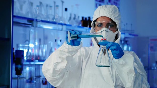 Pours liquid from a beaker into an empty flask.