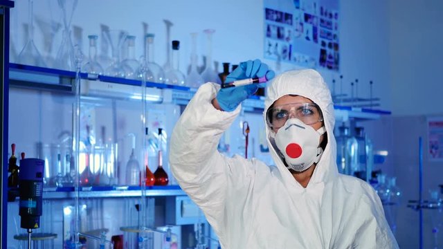 Lab worker examines a test tube.