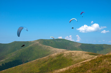 Fototapeta na wymiar Paraglider flying over the picturesque mountains on a sunny summer day