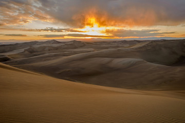 Obraz na płótnie Canvas Sunset at Great Sand Dunes - Spring storm clouds passing over Great Sand Dunes as the sun sets at horizon. Great Sand Dunes National Park & Preserve, Colorado, USA.
