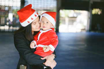 Obraz premium Asian mother holding baby in santa suit