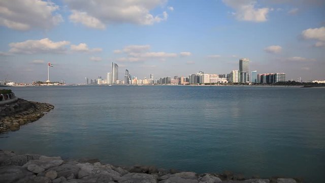 Abu Dhabi skyline with clouds and sea waves bashing. Establishing shot.