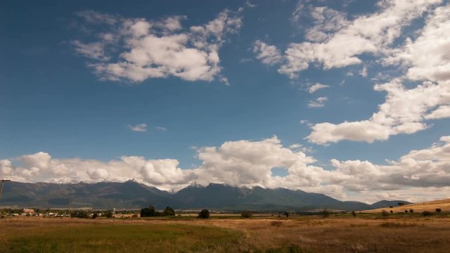 Time lapse clouds travel over plains and mountains.